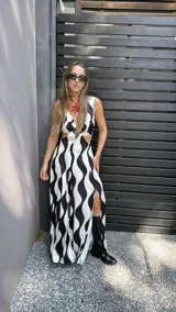 Vestido largo de tela sedosa con estampado de ondas verticales en blanco y negro, escote en V, cut out en la cintura, espalda regulable con lazo y elástico, y tajos laterales.