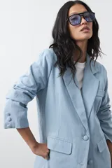 Blazer de jean color celeste con silueta recta y corte sastrero. Presenta solapas clásicas, cierre frontal con botón forrado, bolsillos con tapa y detalle de botones forrados en los puños.