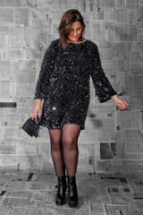 Vestido corto de fiesta color negro, recubierto de lentejuelas, con escote redondo y mangas largas rectas.