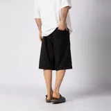 Bermuda sastrera gris de corte baggy, con pinzas al frente y diseño holgado que se extiende por debajo de la rodilla.