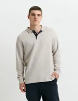Remera de manga larga con cuello polo, confeccionada en tejido de punto canalé francés. Presenta abotonadura frontal con botones de madera y detalles a contratono en la cartera y el interior del cuello.