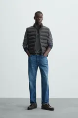 Chaleco acolchado verde oscuro, con cuello alto, cierre frontal con cremallera y bolsillos laterales. Confeccionado en tejido técnico repelente al agua.