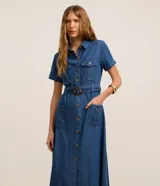Vestido midi de jean con cuello camisero, manga corta y cierre frontal con botones. Cuenta con bolsillos frontales con solapa en el pecho, bolsillos laterales en la falda y cinturón ajustable con hebilla redonda carey.