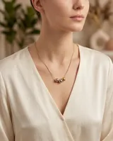Collar de acero con cadena fina y tres dijes centrales en forma de esferas con acabados en plateado, dorado y oro rosa.