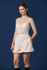 Top tipo corset de encaje negro con escote strapless y copas estructuradas. Presenta detalles de encaje con bordes festoneados y paneles transparentes en el torso.