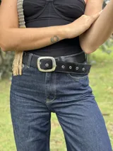 Cinturón negro de cuero con hebilla plateada cuadrada y ojales metálicos.