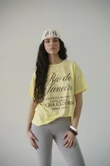 Remera de algodón blanca con estampado frontal en negro que dice "Rio de Janeiro" en letra cursiva y "Captivate Journey to Copacabana Lucha Clothing since 2019".