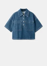 Blusa de algodón estilo denim, con diseño oversize, cuello camisero, mangas cortas, dos bolsillos de parche en el pecho y cierre frontal de botones.