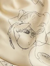 Remera de tirantes color crema con estampado de flores negras, cuello redondo y corte recto.