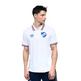 Remera tipo polo de manga corta, color blanco, con cuello y puños con ribetes tricolores (azul, rojo y blanco). Presenta el logo de Umbro y el escudo del Club Nacional de Football bordados en el pecho.