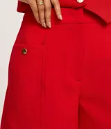 Short sastre de cintura alta, color blanco, con bolsillos laterales y detalles de tachuelas metalizadas.