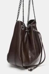 Bolso tipo saca de cuero sintético color marrón oscuro, con diseño fruncido y cierre mediante cordón ajustable. Cuenta con asas de hombro combinadas con cadena metálica y bolsillo interior con cremallera.