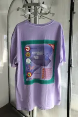 Remera lila de corte holgado con estampado rectangular en la espalda que simula el empaque de un producto de limpieza.