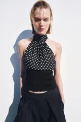 Top de cuello halter con hombros descubiertos, confeccionado con una combinación de tejidos. La parte superior presenta un estampado de lunares, mientras que la parte inferior es de tejido liso acanalado.
