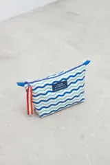 Necessaire de diseño rectangular con estampa de ondas en tonos azules y celestes sobre fondo blanco, con cierre superior y etiqueta frontal con la inscripción Costa Atlántica.