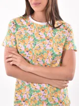 Remera de mangas cortas con cuello redondo y estampado floral en tonos amarillo, naranja, rosa y verde.