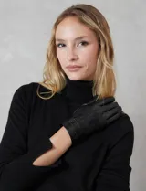 Guantes de cuero sintético color negro, con costuras decorativas en el dorso y detalle de tira con broche a presión en la muñeca. Interior forrado en terciopelo.