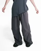 Pantalón unisex gris con pretina elástica, bolsillos laterales y pinzas horizontales en las rodillas.