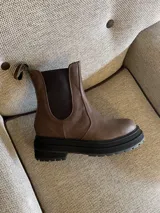 Botas Chelsea de cuero marrón con elásticos laterales negros y suela track negra.