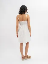 Vestido midi de broderie color blanco, con tirantes finos, escote recto y detalle de botones frontales decorativos.