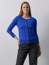 Cardigan blanco de tejido fino con abertura central y botones.