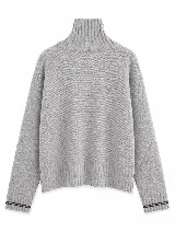 Polera tejida en lambswool color gris, con cuello alto y cierre frontal parcial con detalle en negro. Presenta diseño de tajos laterales en el ruedo, puños acanalados con detalle de rayas en contraste y un pequeño aplique circular con logo en el frente.