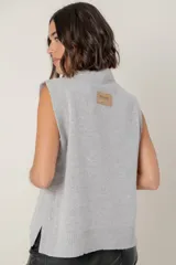 Chaleco de lana color crema con diseño de flor bordada en relieve en el frente, cuello redondo y aberturas laterales en el ruedo.