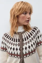 Cardigan de punto con diseño jacquard en tonos beige, marrón y rojo. Presenta cuello redondo, cierre frontal con botones y puños acanalados.