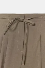 Pantalón culotte de tiro medio color marrón topo, con pliegues marcados en el delantero y cintura ajustable con cordones. Cierre frontal con cremallera y gancho metálico.