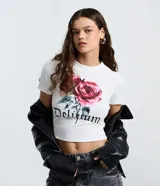 Remera corta y ajustada de color blanco, con cuello redondo y mangas cortas. Presenta un estampado frontal de rosas rojas y la inscripción 'Delirium' en tipografía gótica.