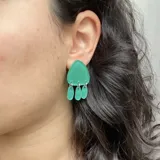 Par de aros colgantes plateados con forma triangular y tres dijes redondos colgando de la base.