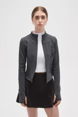 Campera deportiva de ajuste entallado, confeccionada en poliéster color gris oscuro. Presenta cuello alto, cierre frontal completo y mangas largas con aberturas para los pulgares.