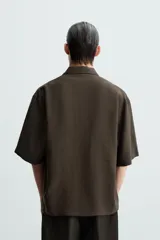 Camisa de corte relajado confeccionada en tejido con mezcla de modal, con cuello solapa, manga corta y cierre frontal de botones.