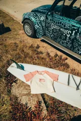 Top corto color crema con mangas cortas color rosa y estampado de palmeras y texto en el frente.