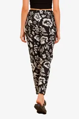 Pantalón de tiro alto con cintura elástica y bolsillos laterales. Presenta un diseño estampado de follaje en color blanco sobre un fondo amarillo.