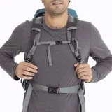 Mochila técnica Merrell modelo Grayling, diseñada para actividades al aire libre. Presenta un diseño ergonómico en color azul, con múltiples compartimentos con cierre, correas de ajuste laterales, cordones elásticos frontales para sujeción de equipo y logo de la marca estampado en la parte superior.