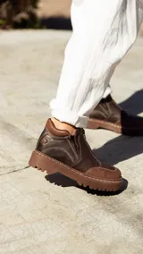 Bota de cuero color marrón chocolate, con cierre frontal con cremallera, costuras en contraste y suela track.