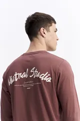 Remera de manga larga color bordó con escote redondo y estampado en la espalda que dice "Mistral Studio limited edition" en blanco.