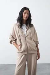 Campera con capucha y cierre frontal, de silueta relajada y hombros caídos. Presenta bolsillos laterales, terminaciones elastizadas en puños y ruedo, y detalles de recortes en el frente con cierre metálico de tirador circular.