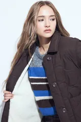 Campera acolchada de color negro con diseño capitoneado, cierre frontal con botones y cuello clásico.