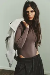 Body de manga larga con cuello redondo, confeccionado en una mezcla de algodón y modal. Presenta cierre inferior con botones a presión.