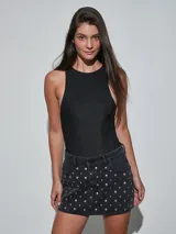 Minifalda de denim gris oscuro con tachas metálicas plateadas distribuidas por toda la prenda, bolsillos delanteros y cierre de botón y cremallera.