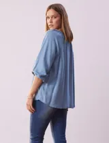 Blusa celeste de tencel con cuello redondo, escote en V y lazo de ajuste. Tiene cuello y escote calado y mangas 3/4 amplias con puño elastizado.