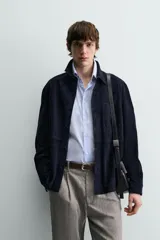 Sobrecamisa de hombre, color azul marino oscuro, confeccionada en piel con acabado ante. Presenta cuello solapa, manga larga con puños abotonados, un bolsillo de parche en el pecho y cierre frontal de botones.