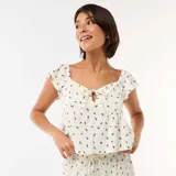 Top de tejido arrugado color blanco con estampado floral oscuro, escote cuadrado con pequeño lazo y recorte frontal, y mangas cortas con volados.