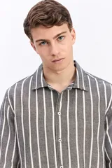 Camisa de manga corta oversize en tejido rústico, con diseño de rayas verticales celestes y blancas, cuello clásico y cierre frontal de botones.