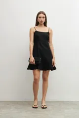 Vestido corto negro de lino con breteles finos, corte recto y volado en el ruedo.