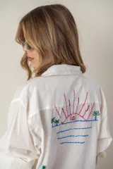 Camisa blanca de manga larga con bordados de motivos playeros.