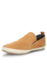 Alpargata Hush Puppies de gamuza color mostaza, con suela de yute trenzado y detalle de elástico lateral con diseño multicolor. Cuenta con forro interior de algodón orgánico.