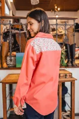 Sobre camisa coral de manga larga, con canesú en la espalda y detalles en los puños de tela estampada con flores.